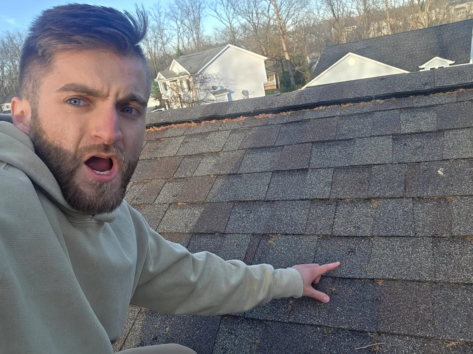 Roofer on a roof pointing out a damaged area of shingles